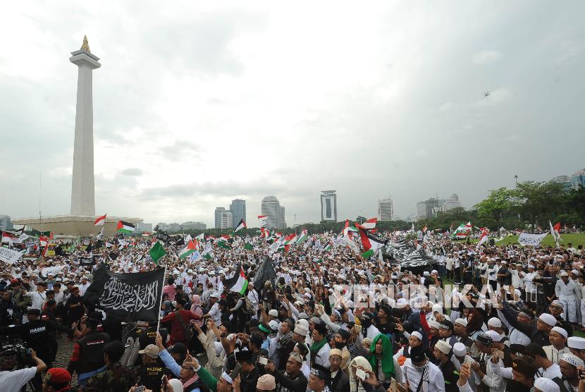 Peserta perempuan aksi solidaritas Palestina mengibarkan bendera dalam aksi solidaritas Palestina di Monumen Nasional, Jakarta, Ahad (17/12).