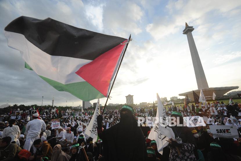 Peserta perempuan aksi solidaritas Palestina mengibarkan bendera dalam aksi solidaritas Palestina di Monumen Nasional, Jakarta, Ahad (17/12). 