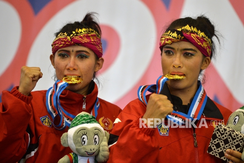 Pesilat Bali Ni Made Dwiyanti dan Sang Ayu Ketut Sidan W menunjukan medali usai tampil dalam final nomor Seni Ganda Putri PON XIX di GOR Graha Laga Satria ITB Jatinangor, Sumedang, Jabar, Sabtu (24/9).