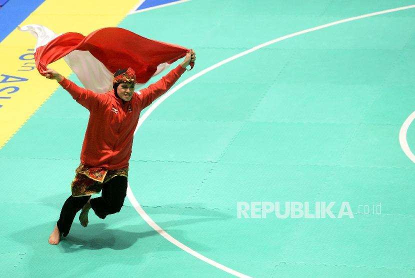 Pesilat Indoensia Puspa Arumsari berlari dengan membawa bendera merah putih usai beraksi pada final cabang pencak silat kelas artistik tunggal putri Asian Games 2018 di Padepokan Pencak Silat TMII, Jakarta, Senin (27/8). Pada pertandingan tersebut Puspa berhasil menyumbangkan medali emas bagi indonesia dengan skor akhir 467.