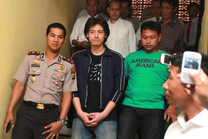Pesinetron dan model Roger Danuarta dikawal petugas kepolisian usai pemeriksaan dirinya terkait penggunaan narkoba di Polsek Pulogadung, Jakarta Timur, Senin (17/2).