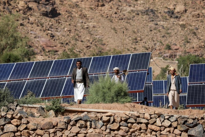 Petani berjalan di tengah panel surya di perkebunan di Wadi Dhahr, dekat Sanaa, Yaman, 28 Oktober 2019. Yaman beralih ke tenaga surya di tengah kekurangan energi akibat perang.