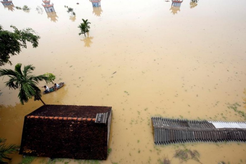 Petani mengayuh sampan di tengah desa yang banjir di Hanoi, Vietnam, Jumat (13/10).
