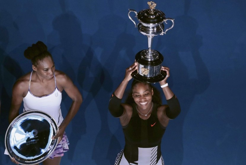 Petenis Amerika Serikat, Serena Williams (kanan) mengangkat trofi Australia Terbuka 2017 setelah mengalahkan Venus Willams pada parta final di Rod Laver Arena, Sabtu (28/1). Serena menang dua set langsung.