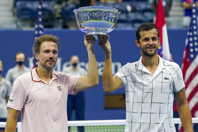  Petenis Brasil Bruno Soares (kiri) dan Mate Pavic dari Kroasia memegang trofi juara ganda putra US Open 2020. Soares/Pavic mengalahan duet Wesley Koolhof (Belanda) dan Nikola Mektic (Kroasia) pada final, Jumat (11/9) WIB.