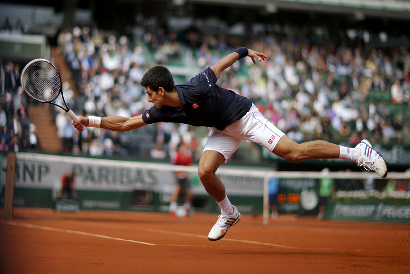  Petenis Serbia, Novak Djokovic, mengembalikan bola pukulan petenis Kanada, Milos Raonic, dalam laga perempat final tunggal putra Prancis Terbuka di Roland Garros, Paris, Selasa (3/6). 