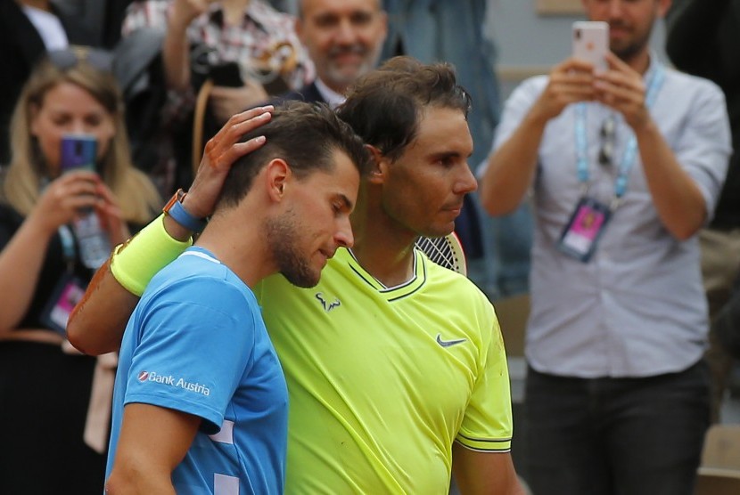  Petenis Spanyol Rafael Nadal (kanan) merangkul rivalnya di final Prancis Terbuka, petensi asal Austria Dominic Thiem, setelah melewati empat set pertandingan di stadion Roland Garros, Ahad (9/6).