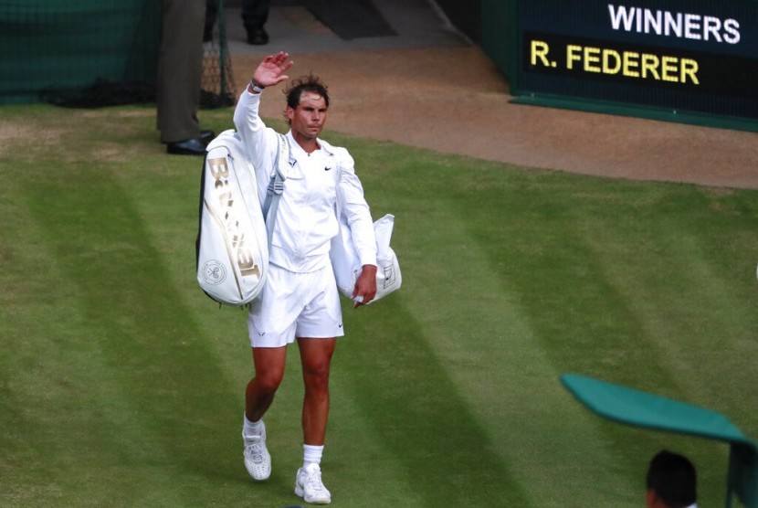 Petenis Spanyol Rafael Nadal melambaikan tangan ke penonton usai bertanding melawan Roger Federer pada semifinal Wimbledon di London, Jumat (12/7) waktu setempat.