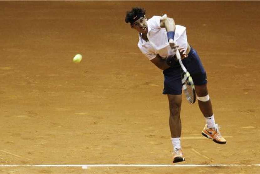 Petenis Spanyol, Rafael Nadal, melepaskan servis saat berduet dengan petenis Argentina, David Nalbandian, menghadapi ganda Spanyol, Pablo Andujar-Guillermo Garcia-Lopez, di turnamen Brazil Terbuka di Sao Paulo, Brazil, Selasa (12/2).  