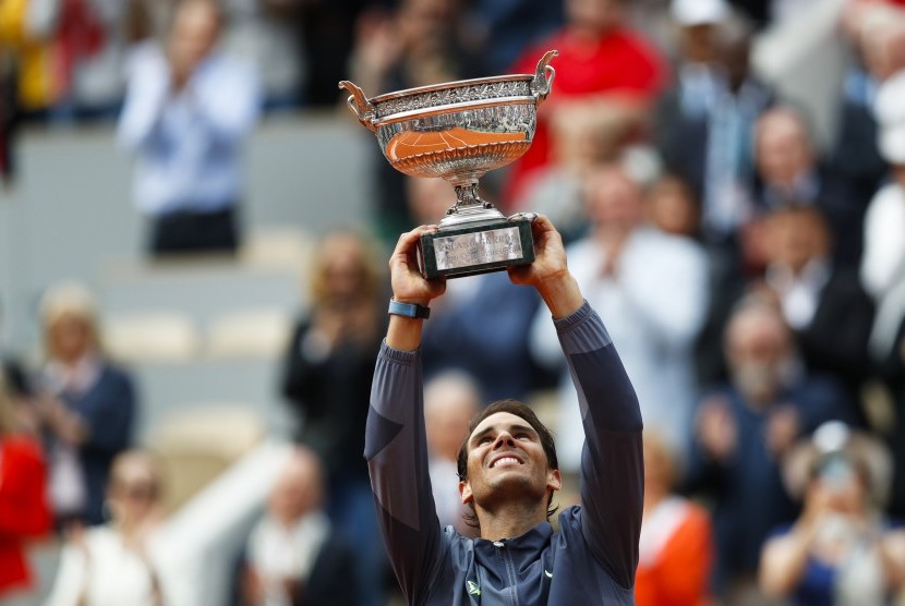 Petenis Spanyol Rafael Nadal mengangkat trofi saat merayakan 12 kali kemenangannya di Prancis Terbuka setelah menaklukkan petenis asal Austria Dominic Thiem dalam empat set pertandingan di stadion Roland Garros, Paris, Ahad.