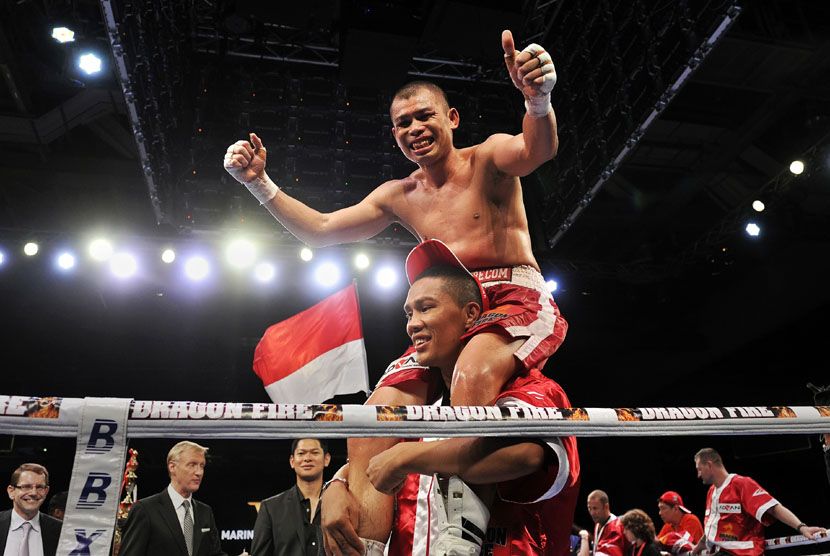    Petinju Chris John merayakan kemenangan usai mengalahkan petinju Thailand Chonlatarn Piriyapinyo di Marina Bay Sands, Singapura, Jumat (9/11) malam. 