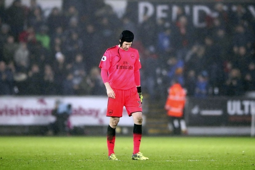 Petr Cech berjalan tertunduk seusai membuat kesalahan yang membuat Arsenal kalah 1-3 dari Swansea City, Rabu (31/1) dini hari WIB.