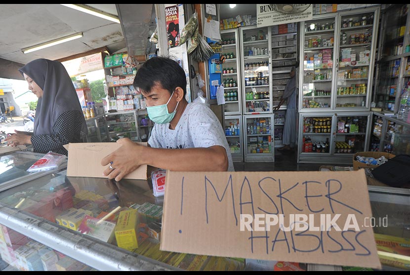 Petugas apotek memasang tanda stok masker habis
