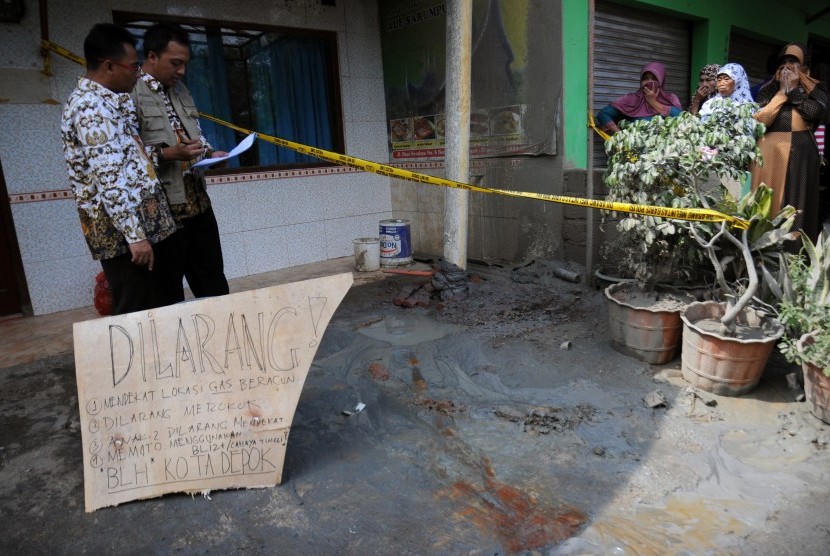 Petugas Badan Lingkungan Hidup Kota Depok memeriksa lokasi semburan lumpur disertai gas beracun yang telah dipasangi pipa di depan RM Padang Serumpun, Jalan Raya Bedahan, Sawangan, Depok, Jawa Barat, Kamis (23/7). 