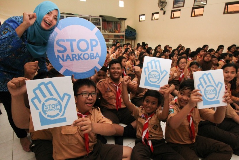 Petugas Badan Narkotika Nasional (BNN) Kota Surabaya bersama pelajar sekolah dasar menyerukan STOP NARKOBA saat sosialisasi bahaya narkoba di Surabaya, Jawa Timur, Jumat (27/1).