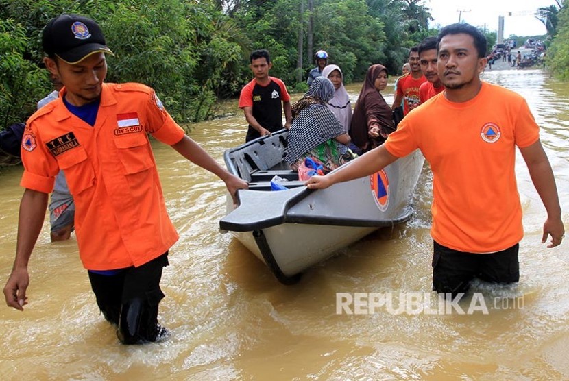 Penanganan Banjir di Aceh Terkendala Anggaran. Petugas Badan Penanggulangan Bencana Daerah (BPBD) Aceh Barat membantu warga yang sakit saat melintasi banjir dengan menggunakan perahu di Desa Pasi Masjid, Kecamatan Meureubo, Aceh Barat, Aceh.