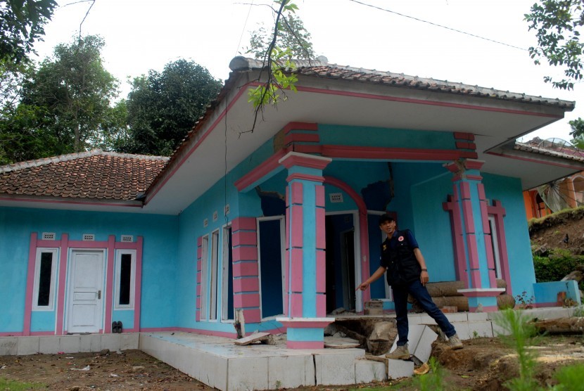 Petugas Badan Penanggulangan Bencana Daerah (BPBD) menunjukkah retakan di salah satu rumah yang rusak berat akibat bencana pergerakan tanah di Desa Nagrak Jaya, Kecamatan Curug Kembar, Sukabumi, Jawa Barat, Kamis (18/8).