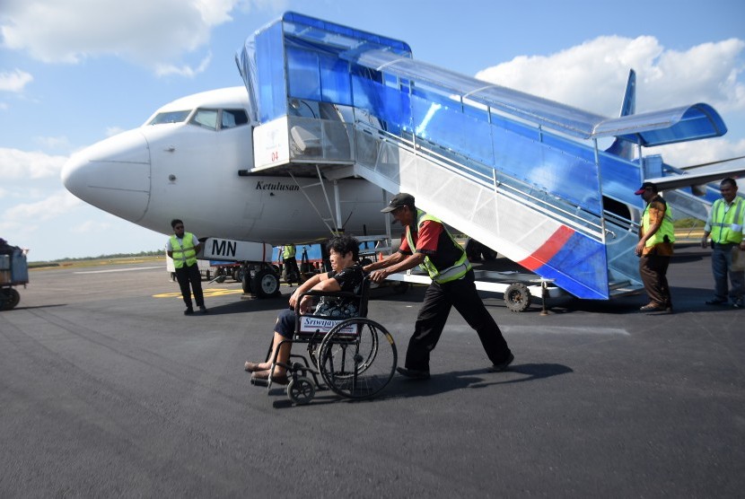 Seribu Warga China Masuk ke Bangka Tiap Tahun. Petugas bandara membantu penumpang lansia menyeberangi landasan saat tiba di Bandara HAS Hanandjoeddin, Belitung, Kepulauan Bangka Belitung. 