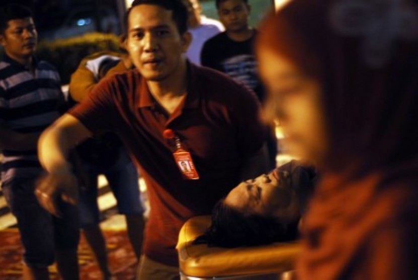 Petugas bandara membawa seorang penumpang yang mengalami 'shock' usai evakuasi pesawat Citilink, di Bandara Internasional Minangkabau (BIM), Padang pariaman, Sumatera Barat, Ahad (2/8) malam. 