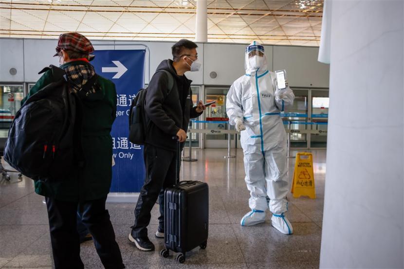 Petugas bandara yang mengenakan pakaian pelindung meminta penumpang untuk menunjukkan formulir keluar pernyataan kesehatan mereka sebelum keberangkatan di Bandara Internasional Ibukota Beijing di Beijing, China.