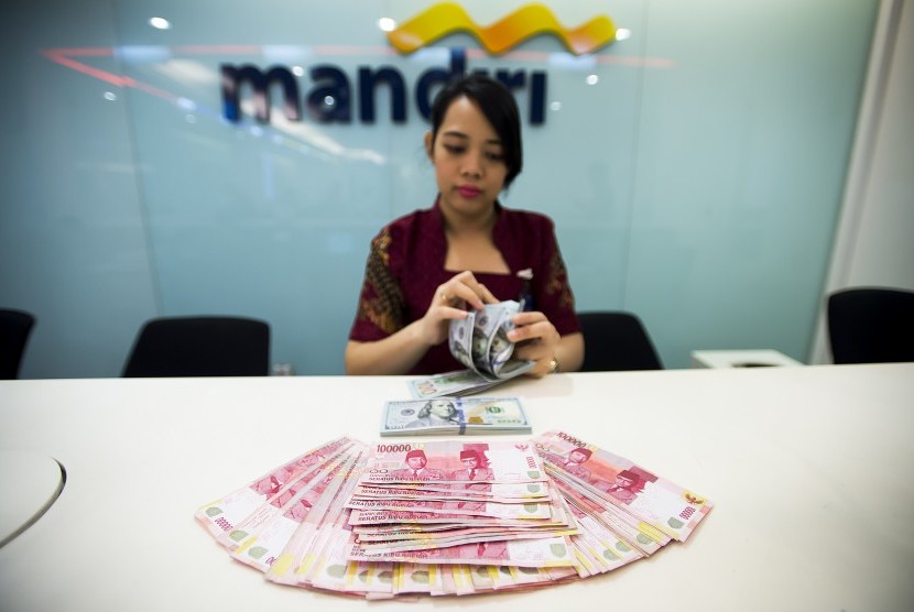 Petugas Bank Mandiri menghitung pecahan uang rupiah dan dollar Amerika Serikat di Jakarta, Jumat (18/3).