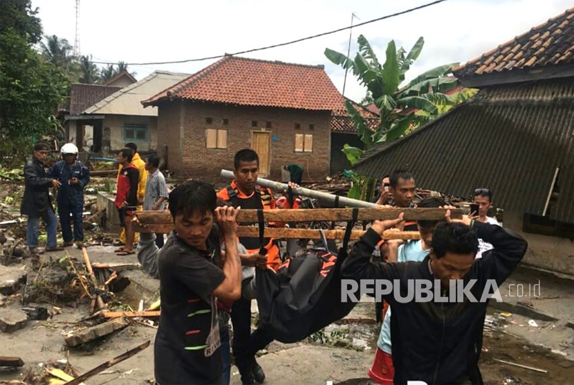 Petugas Basarnas dibantu warga mengevakuasi korban meninggal akibat tsunami di pesisir Cinangka, Serang, Banten, Ahad (23/12). 