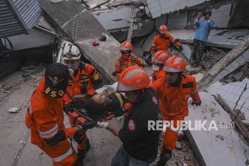 Petugas Basarnas membawa korban selamat gempa dan tsunami yang terjebak di dalam restoran Dunia Baru, Palu, Sulawesi Tengah, Minggu (30/9).
