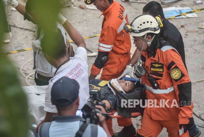 Petugas Basarnas membawa korban selamat gempa dan tsunami yang terjebak di dalam restoran Dunia Baru, Palu, Sulawesi Tengah, Ahad (30/9).