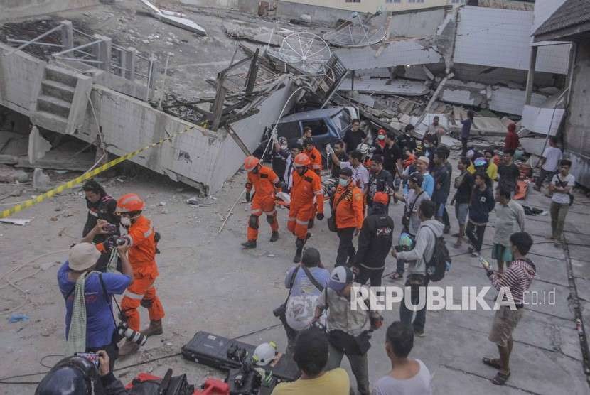 Petugas Basarnas membawa korban selamat gempa dan tsunami yang terjebak di dalam restoran Dunia Baru, Palu, Sulawesi Tengah, Ahad (30/9).