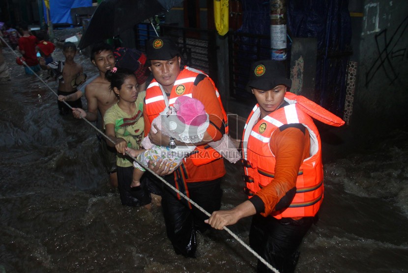   Petugas Basarnas mengevakuasi korban banjir di kawasan Kampung Pulo, Jakarta, Ahad (12/1).  (Republika/Yasin Habibi)