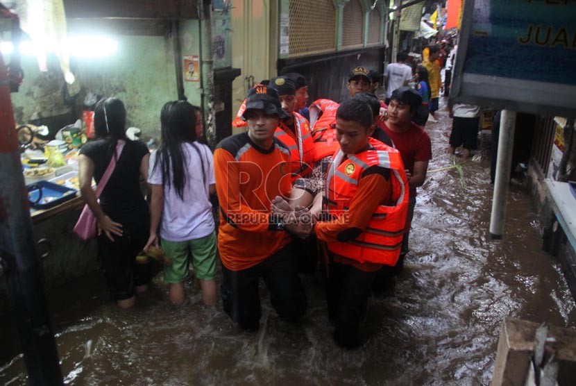  Petugas Basarnas mengevakuasi korban banjir di kawasan Kampung Pulo, Jakarta, Ahad (12/1).  (Republika/Yasin Habibi)