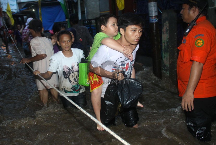   Petugas Basarnas mengevakuasi korban banjir di kawasan Kampung Pulo, Jakarta, Ahad (12/1).  (Republika/Yasin Habibi)