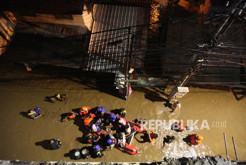 Petugas Basnas melakukan evakuasi warga menggunakan perahu karet saat banjir di kawasan Cililitan, Jakarta, Senin (5/2) malam. Banjir yang merendam kawasan tersebut akibat luapan Kali Ciliwung yang merupakan kiriman dari Bendung Katulampa, Bogor.