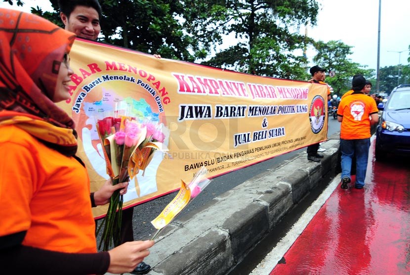 Petugas Bawaslu Jabar memperlihatkan bunga dan stiker sebagai bentuk sosialisasi pemilu bersih di Jalan Surapati, Bandung, Kamis(27/3).  (foto: Septianjar Muharam)