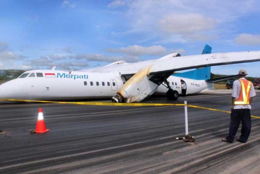 Petugas berada di sisi Pesawat Merpati Nusantara Airlines (MNA) yang tergelincir dan patah di landasan pacu Bandara El Tari Kupang, NTT, Senin (10/6). 