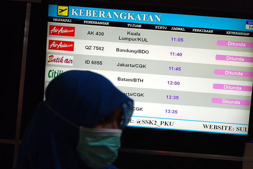 Petugas berdiri di dekat monitor yang menginformasikan penundaan sejumlah penerbangan akibat kabut asap di Bandara Sultan Syarif Kasim II, di Pekanbaru, Riau, Senin (14/9).  (Antara/Rony Muharman)