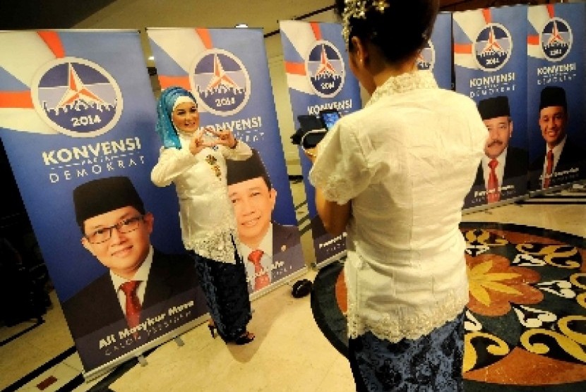 Petugas berfoto di depan poster konvensi calon presiden Partai Demokrat di Jakarta, Ahad (15/9) malam. Konvensi calon presiden Partai Demokrat diikuti oleh 11 orang calon baik dari dalam partai atau non partai.