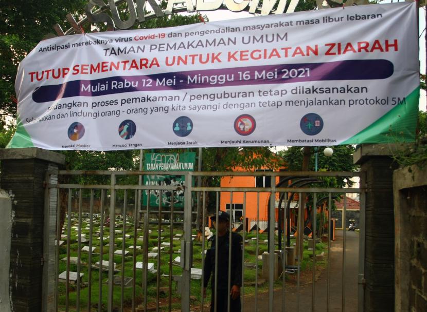 Petugas berjaga di gerbang masuk Tempat Pemakaman Umum (TPU) Sukabumi Selatan yang ditutup di Jakarta Barat, Rabu (12/5/2021). Pemrov DKI Jakarta melarang warga Ibu Kota untuk melaksanakan ziarah kubur saat merayakan Hari Raya Idul Fitri 1442 H dari tanggal 12 Mei 2021 hingga 16 Mei 2021 untuk mencegah penularan dan penyebaran COVID-19.