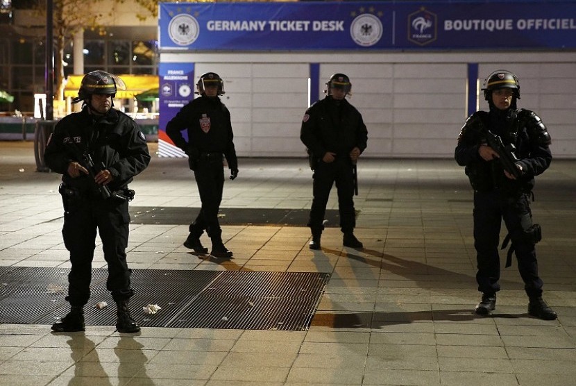 Petugas berjaga di luar stadion Paris yang dihantam bom, Jumat (13/11) malam.