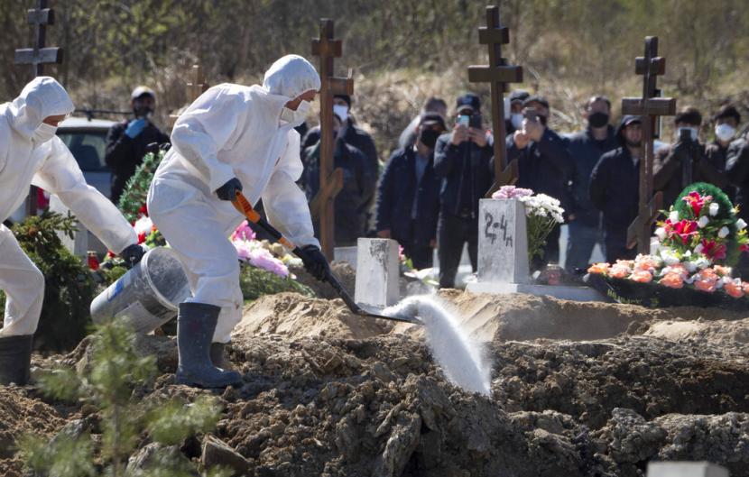 Petugas berpakaian lengkap melakukan penguburan terhadap jenazah pasien Covid-19 di Koplino, Rusia, beberapa waktu lalu.