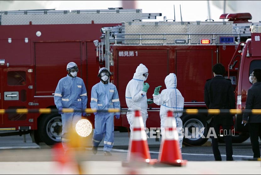 Petugas berpakaian pelindung berdiri di dekat kapal pesiar Diamond Princess berlabuh di Pelabuhan Yokohama untuk mengisi perbekalan di Yokohama, Jepang, Kamis (6/2).  Petugas kesehatan mengkonfirmasi 10 kasus baru positif virus corona selain temuan 10 kasus Rabu kemarin.