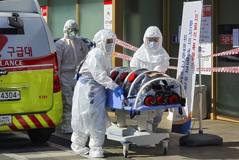  Petugas berpakaian pelindung lengkap membawa pasien yang terinfeksi virus corona dari ambulan ke Kyungpook National University Hospital di Daegu, Korea Selatan. 