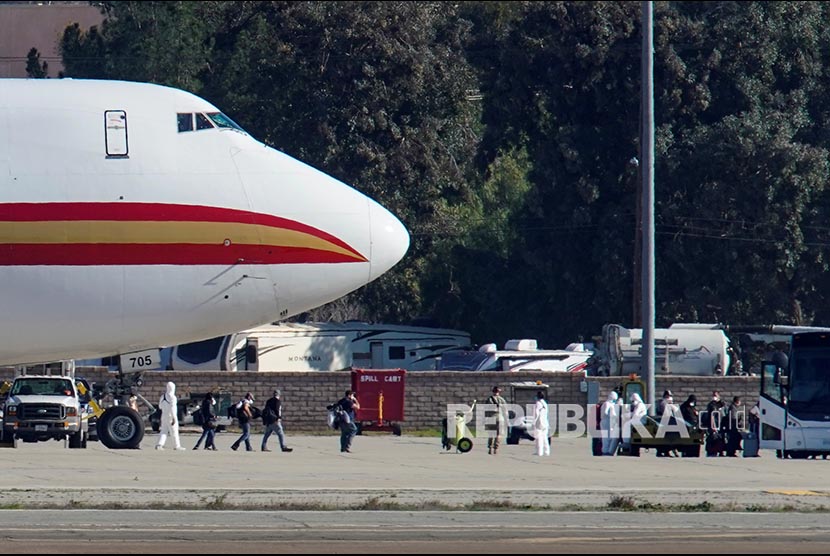 Petugas berpakaian pelindung menurunkan warga AS yang dievakuasi dari Kota Wuhan, mendarat di March Air Reserve Base, Riverside County, California, Amerika Serikat, Rabu (29/1) waktu setempat.
