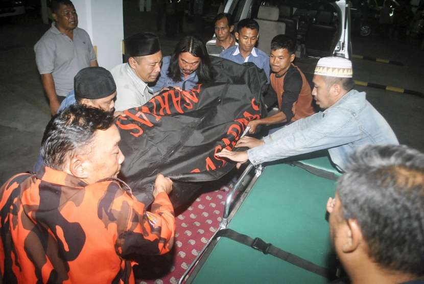 Petugas bersama anggota keluarga memindahkan jenazah korban kecelakaan di Cikidang, Sukabumi, di Rumah Duka Sinar Kasih, Bogor, Jawa Barat, Minggu (9/9).