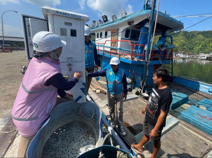 Petugas bersama Srikandi PLN Unit Pelaksana Pelayanan Pelanggan (UP3) Sibolga sedang berbincang dengan salah satu pemilik kapal ikan, Hutagalung (kanan) yang sedang menggunakan SPLU saat bersandar di Tempat Pelelangan Ikan (TPI) Kecamatan Sarudik, Kabupaten Tapanuli Tengah.