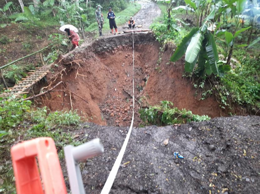Petugas bersama warga membuat jembatan darurat di lokasi jalan yang terputus longsor di Desa Tobongjaya, Kecamatan Cipatujah, Kabupaten Tasikmalaya, Selasa (14/9).