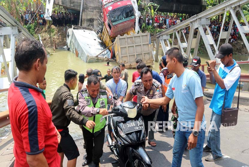 Petugas bersama warga mengevakuasi sepeda motor yang tercebur dalam kejadian runtuhnya jembatan Widang, di Tuban, Jawa Timur, Selasa (17/4). 