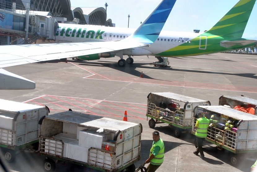 Petugas bersiap memasukkan barang bawaan penumpang ke dalam pesawat di Bandara Internasional Sultan Hasanuddin, Makasar, Sulawesi Selatan, Jum