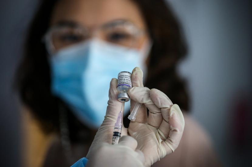Petugas bersiap menyuntikkan vaksin Covid-19.  Warga yang terlambat mendapatkan vaksinasi dosis kedua hingga enam bulan diminta mengulang vaksinnya dari awal. Tujuannya demi mendapatkan proteksi dari penyebaran Covid-19 yang kini sedang meningkat.