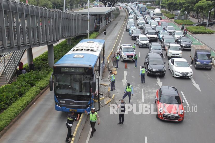 Petugas berupaya mengevakuasi bus TransJakarta yang menabrak separator di Jalan Jenderal Sudirman, Jakarta, Jumat (3/12/2021). Menurut petugas penyebab kecelakaan bus TransJakarta bernomor polisi B 7277 TGC itu diduga akibat sopir yang kurang konsentrasi saat mengemudi.